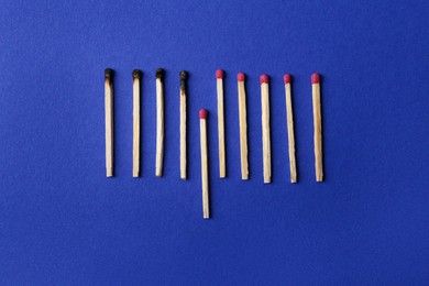 Photo of Burnt and whole matches on blue background, flat lay. Stop destruction concept