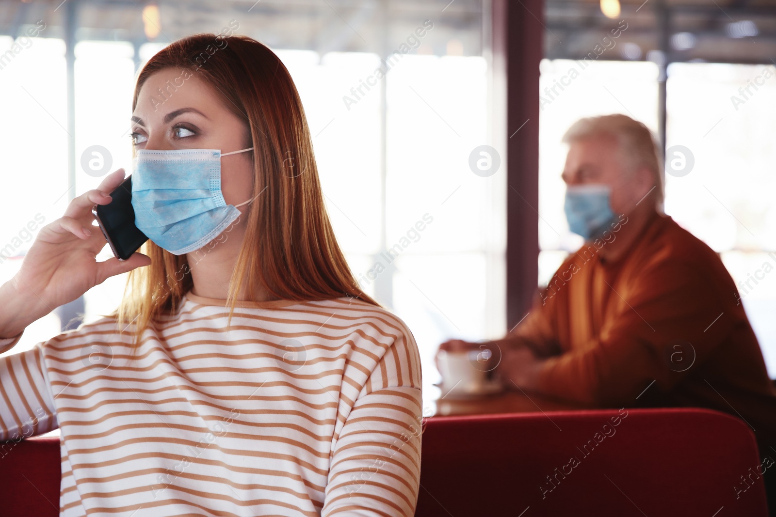 Photo of Woman with medical mask talking on mobile phone in cafe. Virus protection