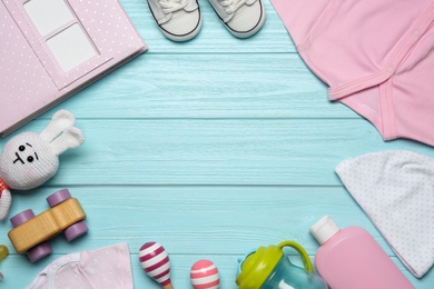 Photo of Frame of baby clothes and accessories on light blue wooden background, flat lay. Space for text