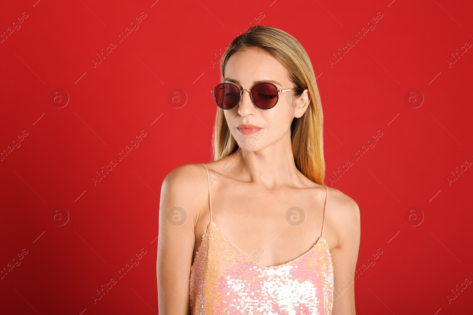 Photo of Beautiful woman in stylish sunglasses on red background