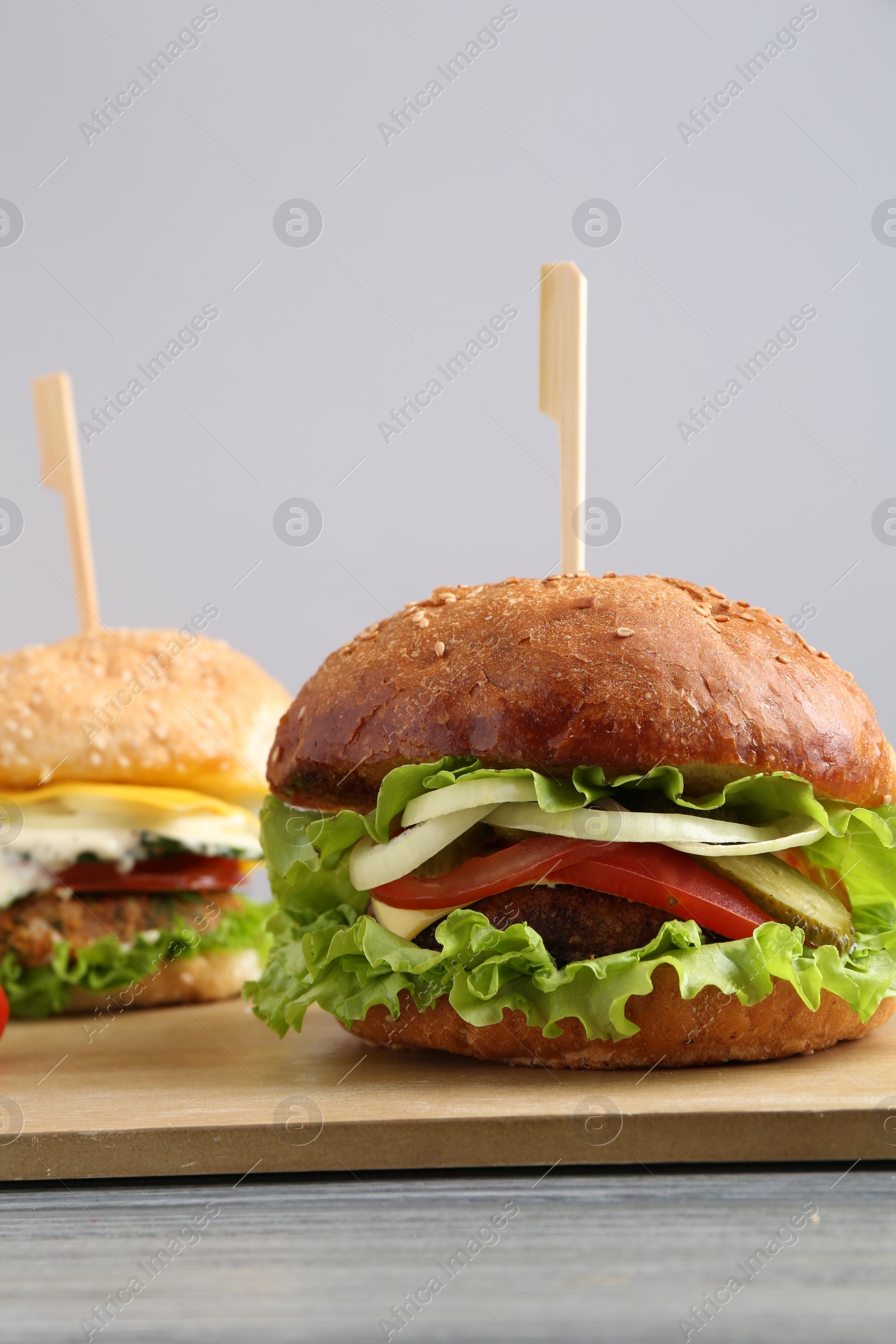 Photo of Delicious vegetarian burgers served on grey wooden table