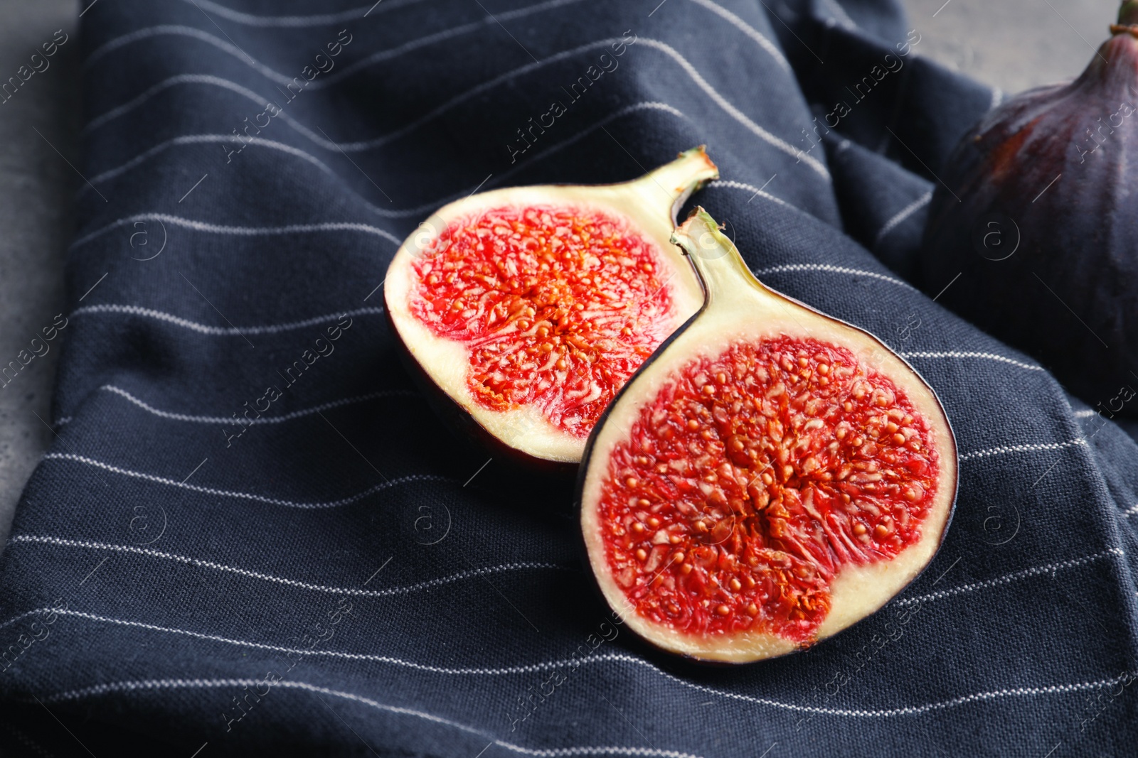 Photo of Fresh ripe sliced figs on fabric. Tropical fruit