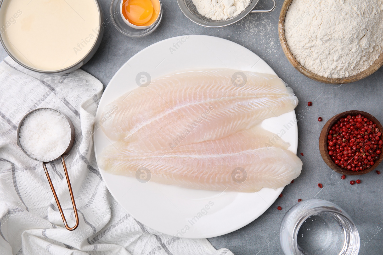 Photo of Different ingredients for soda water batter and raw fish fillet on grey table, flat lay