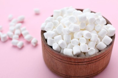 Photo of Bowl with delicious marshmallows on pale pink background, closeup
