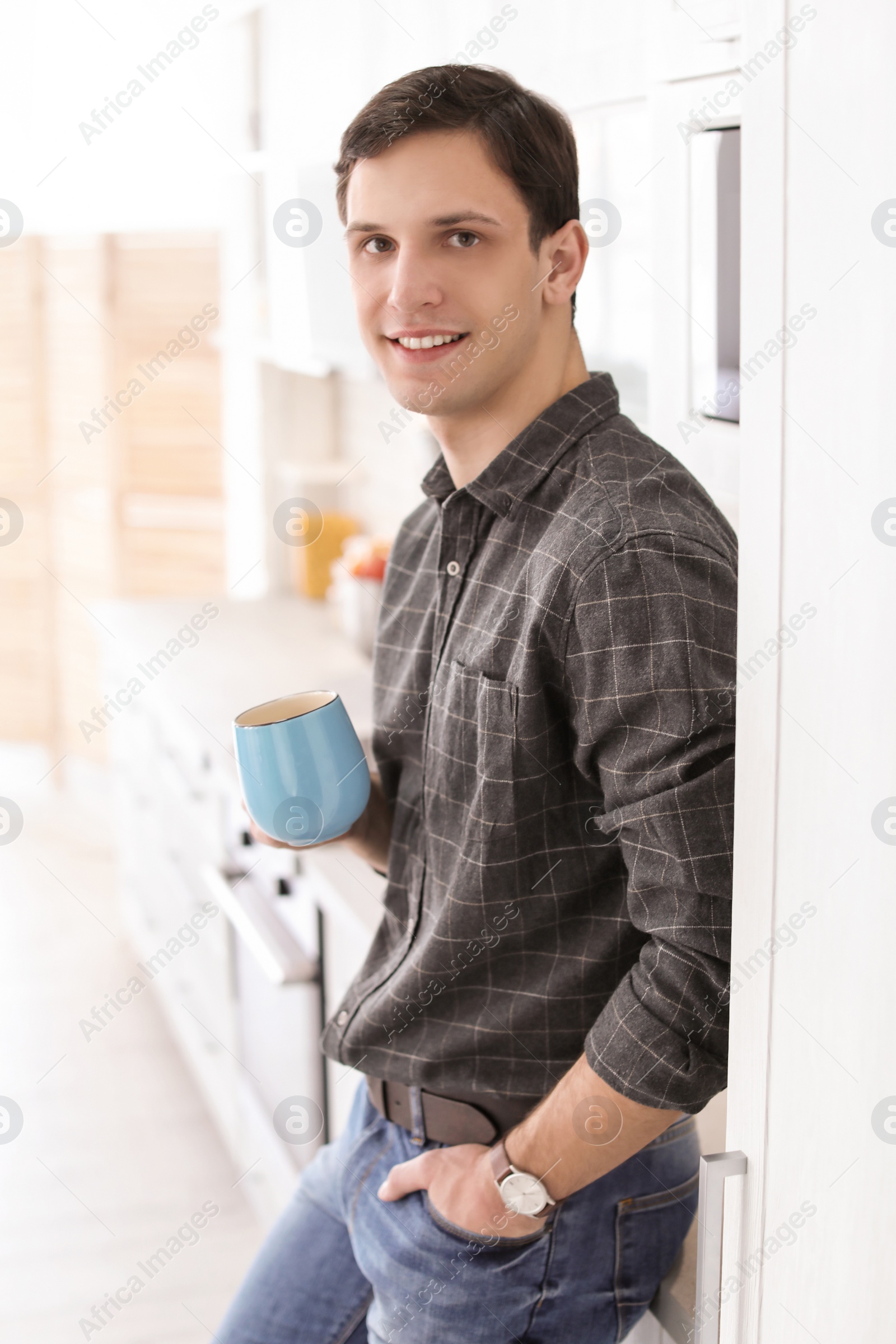 Photo of Portrait of confident young man with cup in kitchen