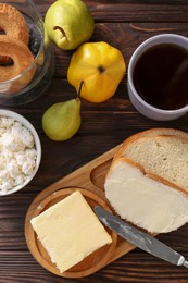 Photo of Tasty homemade butter, bread slices and tea on wooden table, flat lay