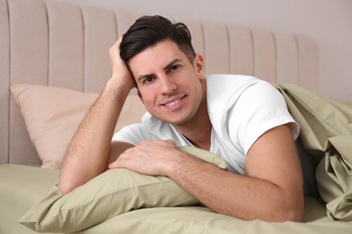 Man lying in comfortable bed with green linens