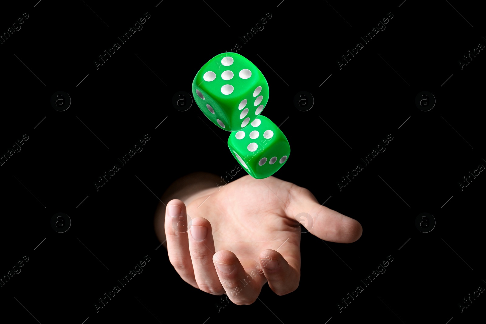 Image of Man throwing green dice on black background, closeup