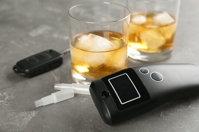 Modern breathalyzer and alcohol on grey stone table