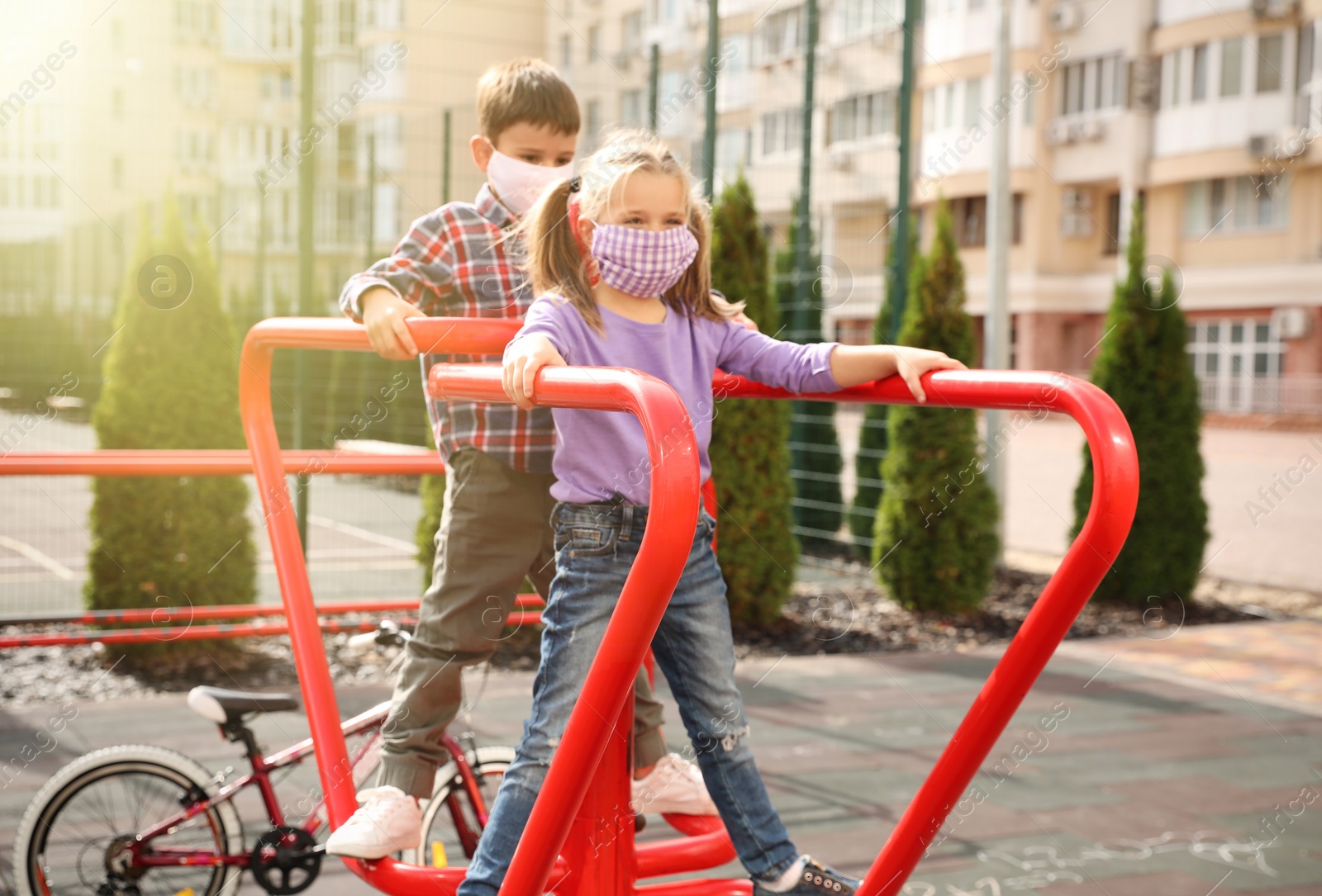 Photo of Little children with medical face masks on playground during covid-19 quarantine