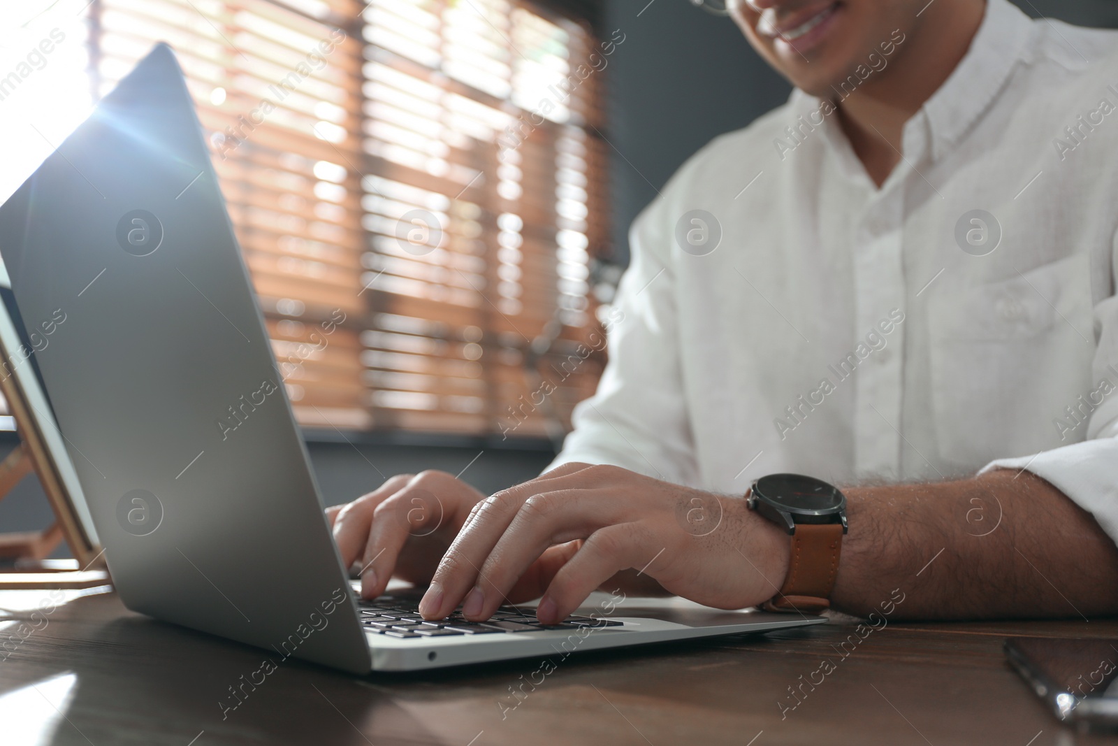 Photo of Freelancer working on laptop at table indoors, closeup