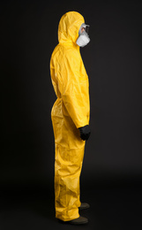 Man wearing chemical protective suit on black background. Virus research