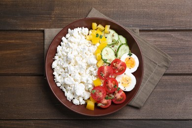 Delicious cottage cheese with vegetables and boiled egg served for breakfast on wooden table, top view