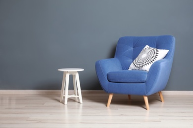 Comfortable armchair and white table against dark wall