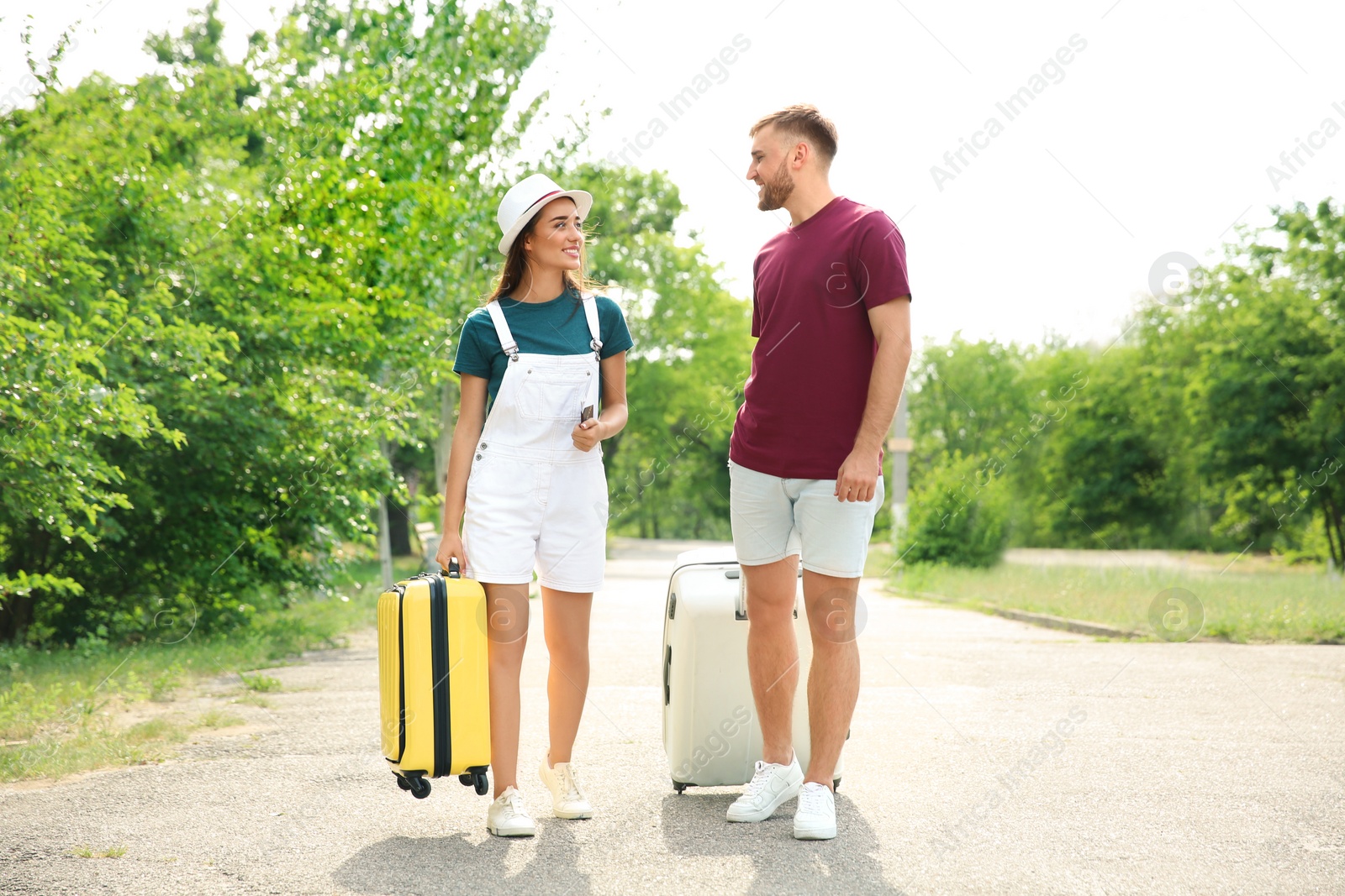 Photo of Beautiful young couple with suitcases packed for summer journey walking outdoors
