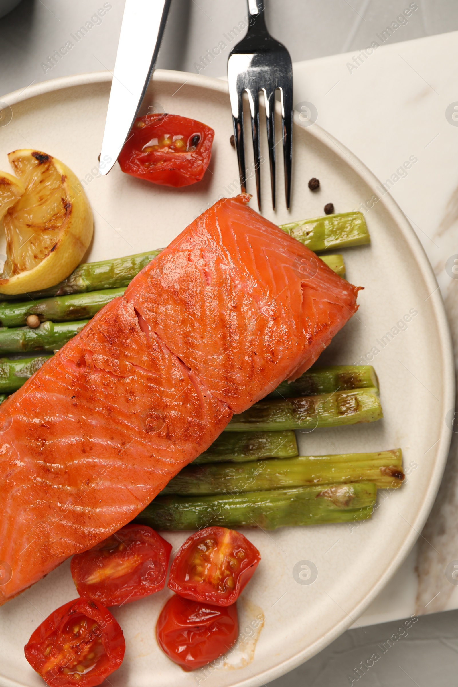 Photo of Tasty grilled salmon with asparagus, tomatoes, spices and lemon served on light grey table, top view