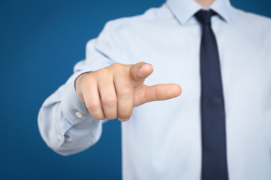 Photo of Businessman touching something against blue background, focus on hand