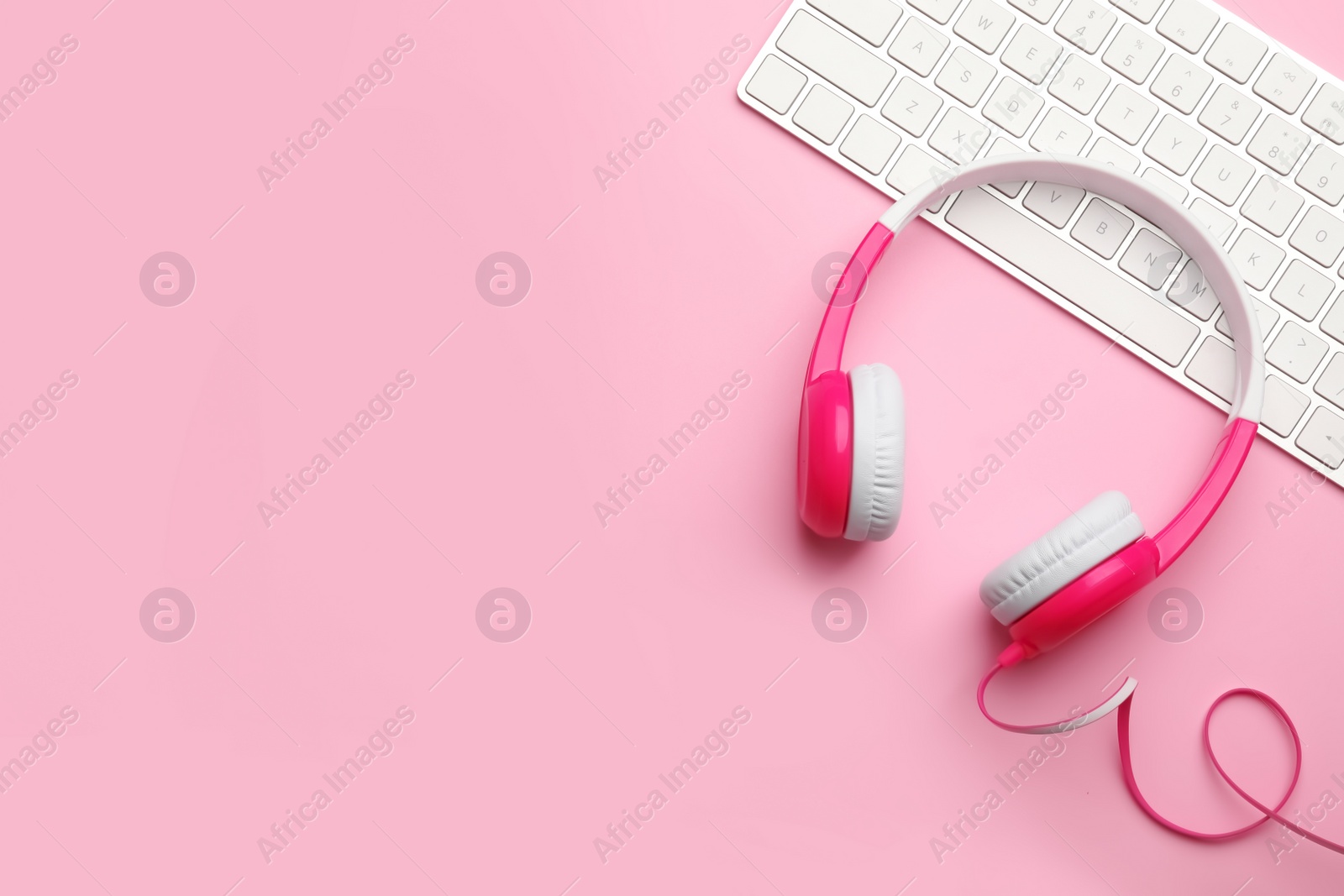 Photo of Modern headphones and keyboard on color background, flat lay. Space for text