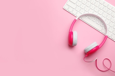 Photo of Modern headphones and keyboard on color background, flat lay. Space for text