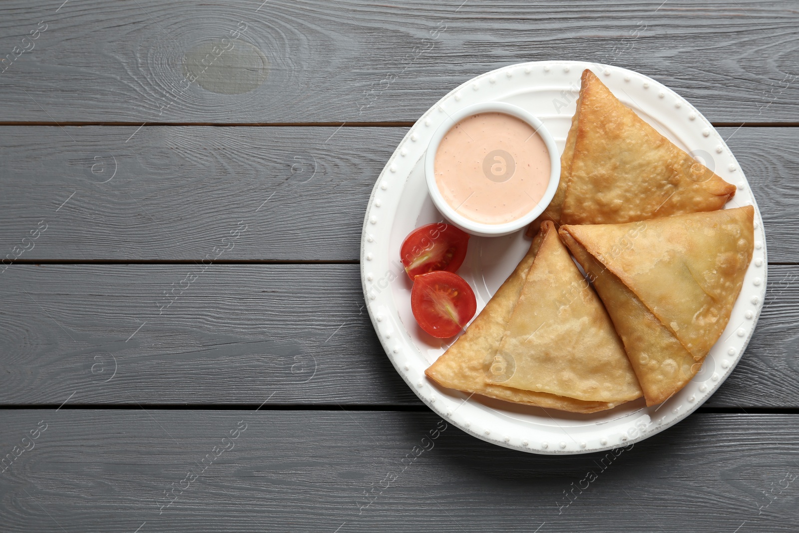 Photo of Fresh delicious crispy samosas served on grey wooden table, top view. Space for text