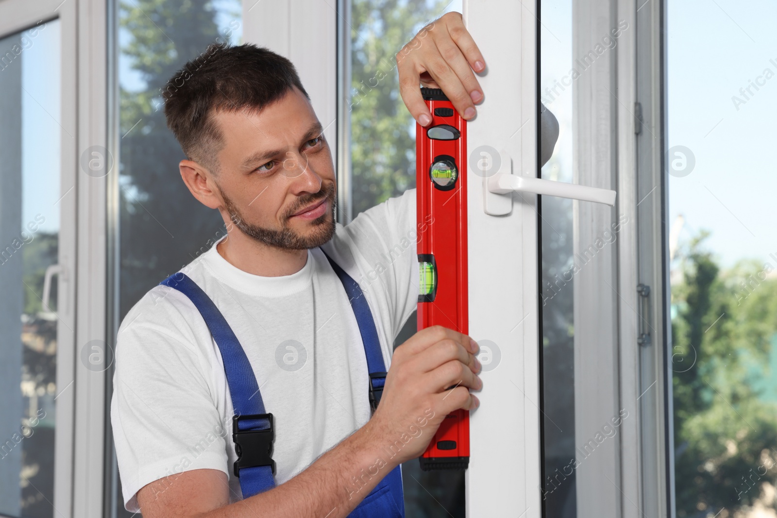 Photo of Worker using bubble level after plastic window installation indoors