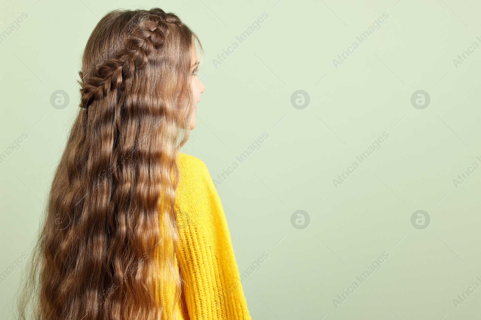 Photo of Cute little girl with braided hair on light green background. Space for text