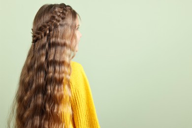 Photo of Cute little girl with braided hair on light green background. Space for text