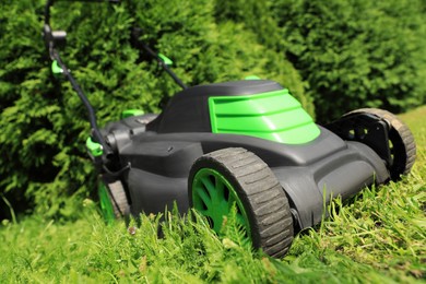 Photo of Cutting green grass with lawn mower in garden