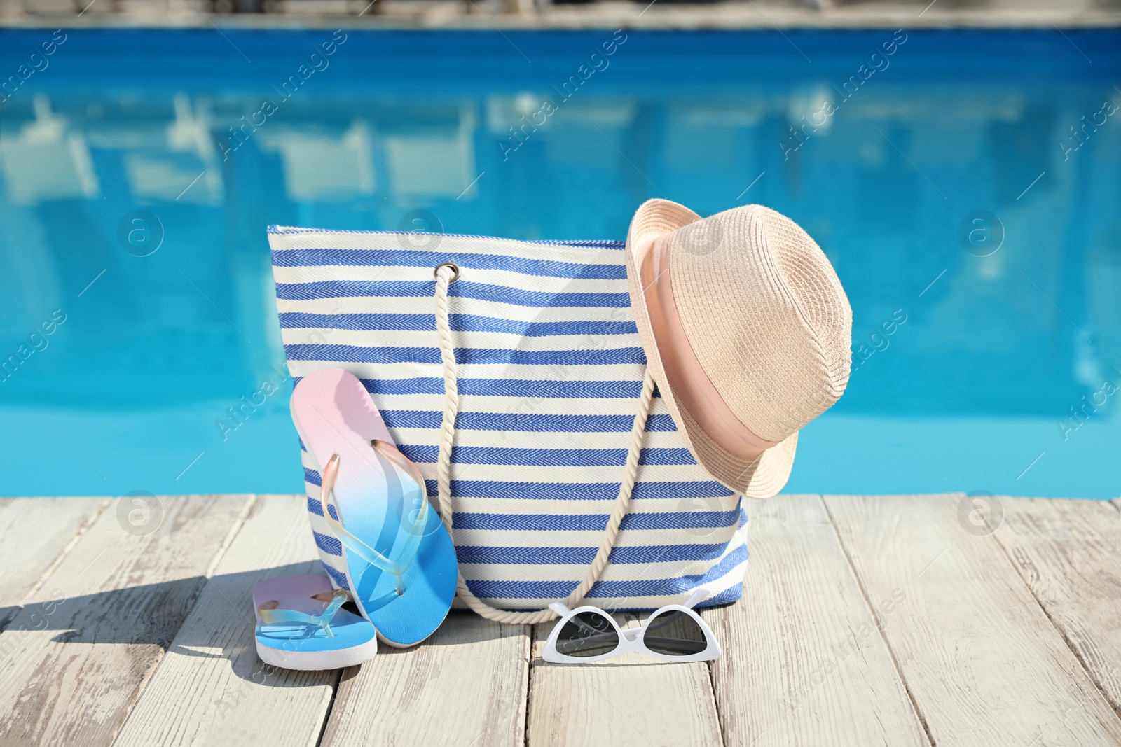 Photo of Beach accessories on wooden deck near outdoor swimming pool