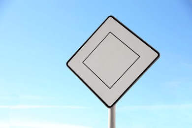 Priority road sign against blue sky on city street
