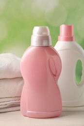 Bottles of laundry detergents and clean clothes on white wooden table