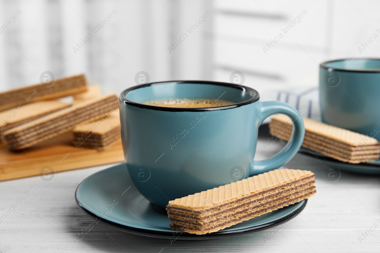 Photo of Delicious wafers and coffee for breakfast on white wooden table