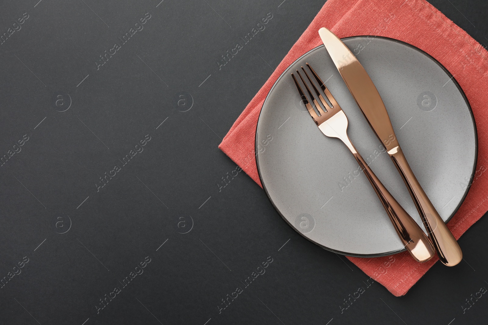 Photo of Clean plate, cutlery and napkin on grey table, top view. Space for text