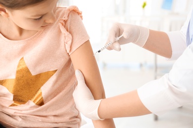 Doctor vaccinating little girl in hospital