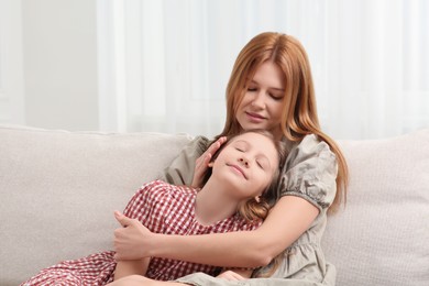 Photo of Mother and her cute daughter on sofa at home