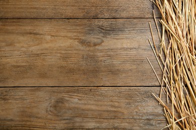 Dried hay on wooden background, flat lay. Space for text