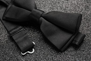 Photo of Stylish black bow tie on dark stone background, closeup