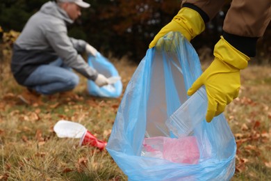Photo of People with trash bags collecting garbage in nature, closeup