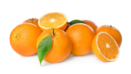 Photo of Cut and whole fresh ripe oranges with green leaves on white background