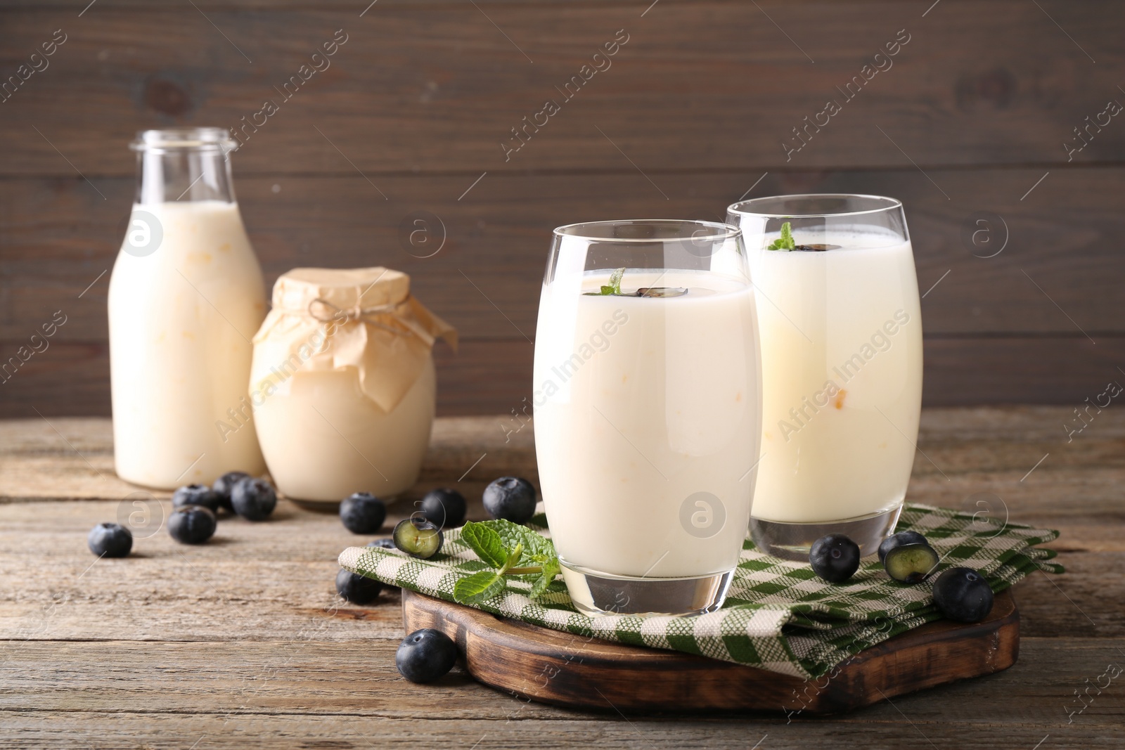 Photo of Tasty yogurt in glasses and blueberries on wooden table, closeup