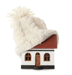 Photo of House model with knitted hat on roof against white background. Heating concept