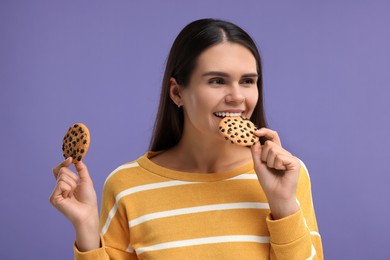 Young woman with chocolate chip cookies on purple background