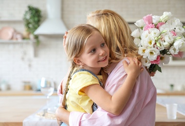 Photo of Cute little girl with bouquet hugging her grandmother in kitchen. Space for text