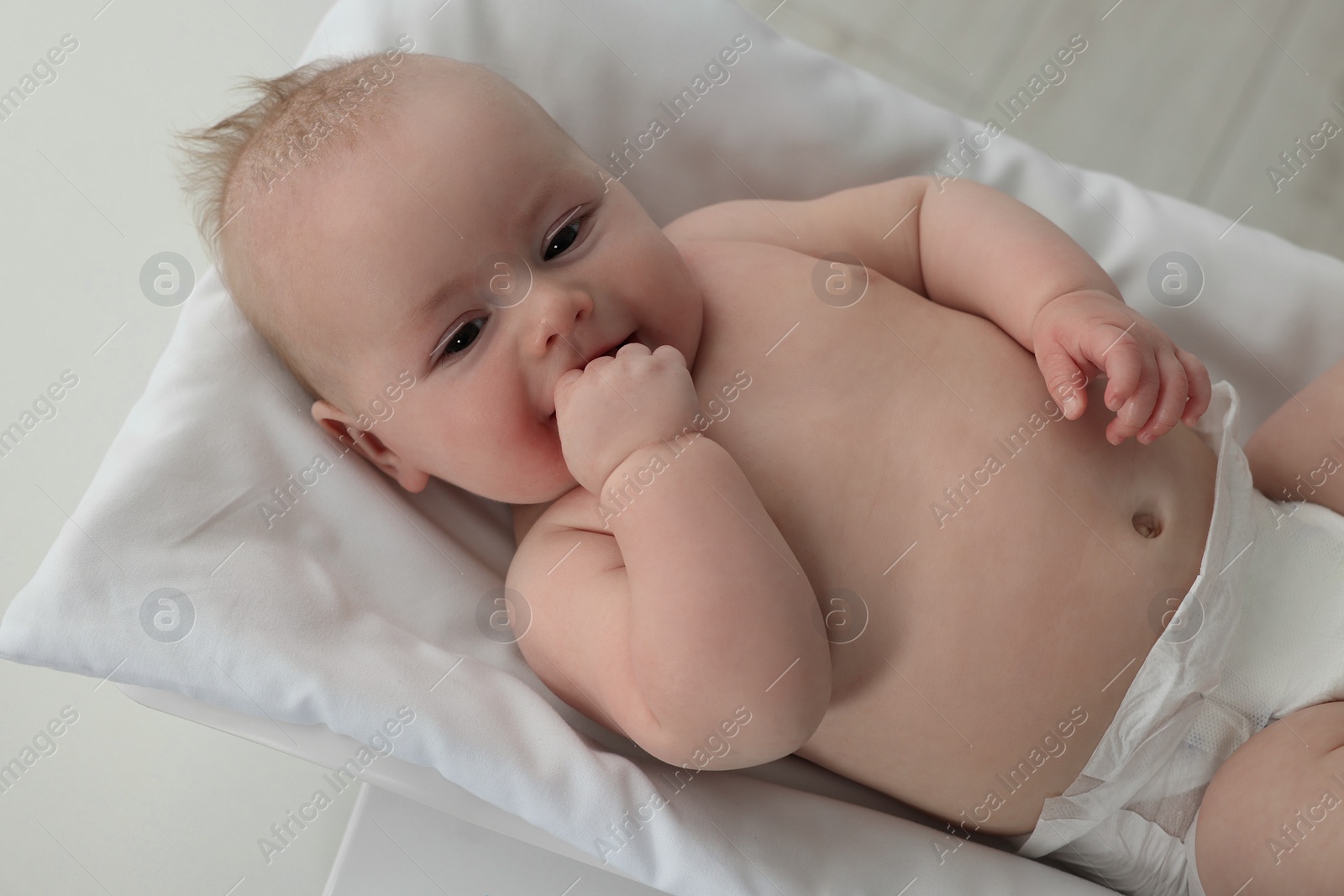 Photo of Cute little baby lying on scales in clinic