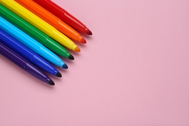 Photo of Many different colorful markers on light pink background, flat lay. Space for text