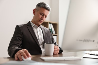 Photo of Man with cup of drink snoozing at table in office