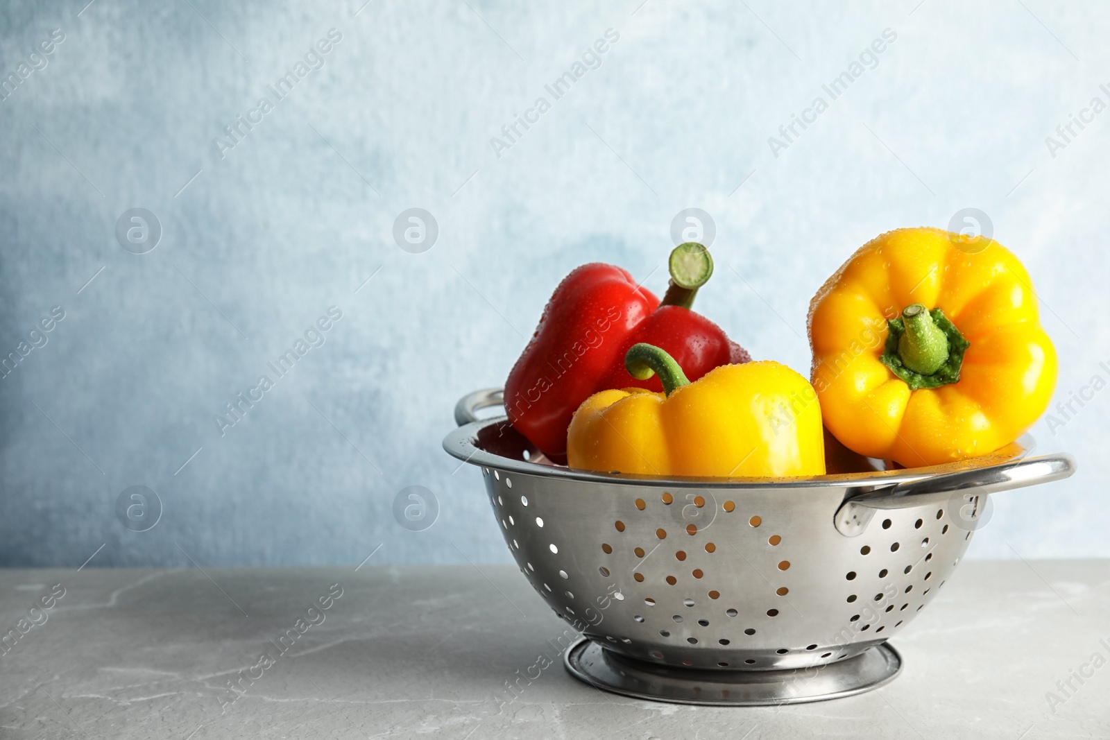 Photo of Colander with ripe paprika peppers on table