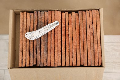 Photo of Box with many decorative bricks and utility knife indoors, above view
