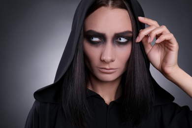 Photo of Mysterious witch with spooky eyes on dark background, closeup