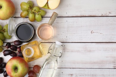 Photo of Different types of vinegar and ingredients on wooden table, flat lay. Space for text